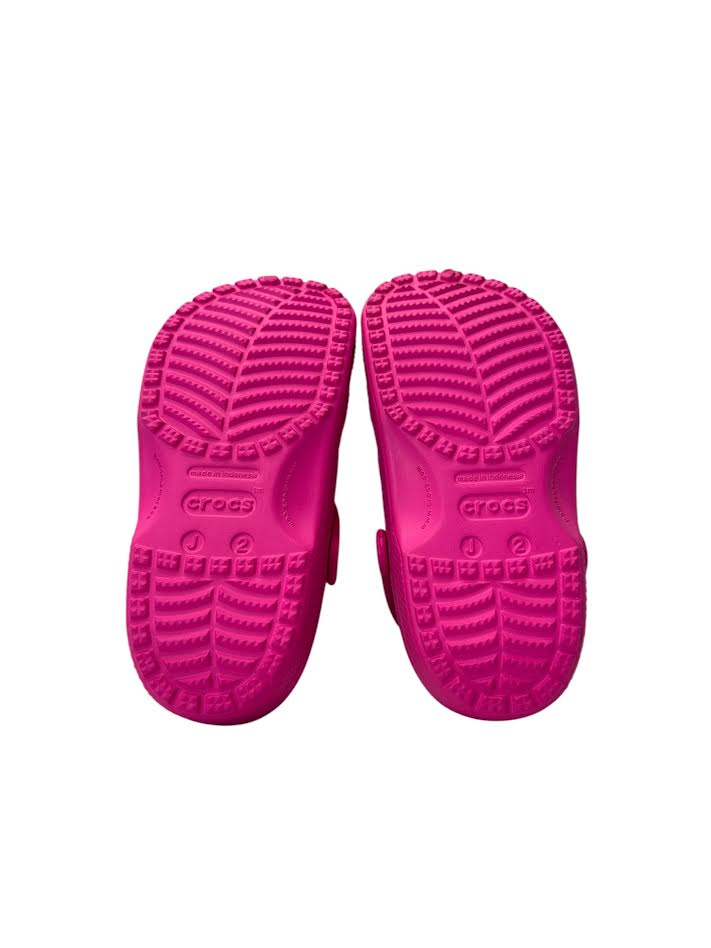 Pink children's shoes with textured soles on a white background