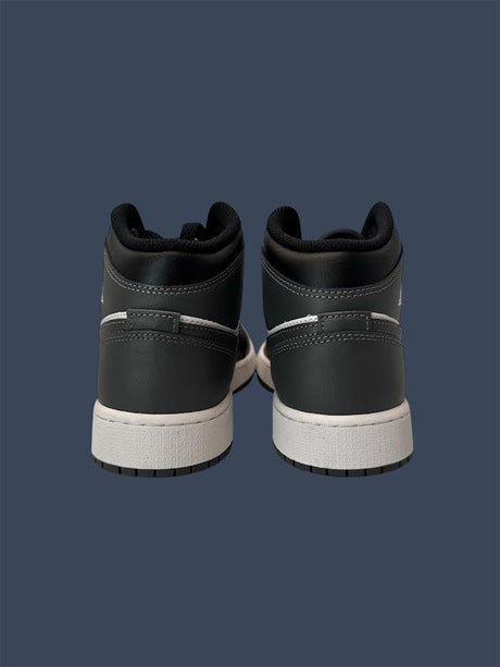 Black high-top sneakers with white soles on a dark blue background