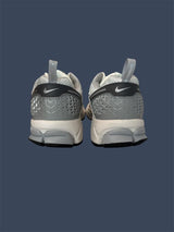 Gray and white Nike sneakers on a dark blue background